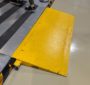 Side view of a yellow anti-slip metal ramp connecting different floor heights in a factory.