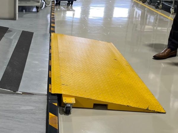 Wide view of industrial yellow ramp with diamond plate surface and black-yellow safety markings.
